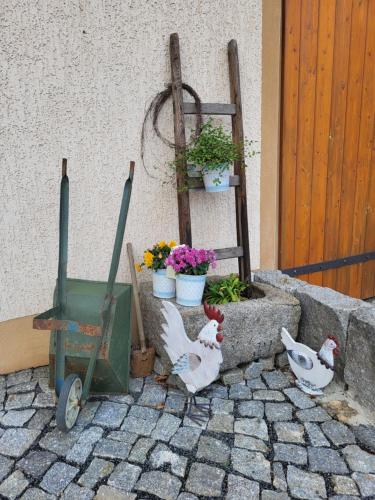 two chickens are standing next to a flower garden at Ferienwohnung Am Wasserturm mit kleinem Bauernhof in Baruth
