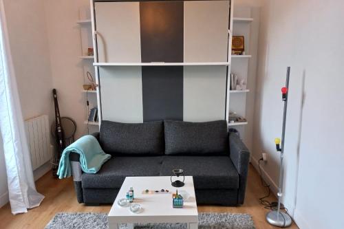 ein Wohnzimmer mit einem Sofa und einem Tisch in der Unterkunft Cozy studio ideal for a romantic holiday in Montreuil