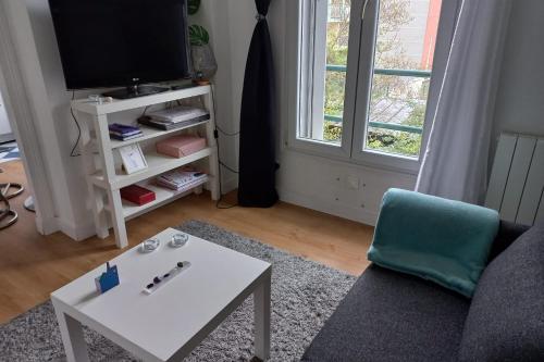 ein Wohnzimmer mit einem Sofa, einem Tisch und einem TV in der Unterkunft Cozy studio ideal for a romantic holiday in Montreuil