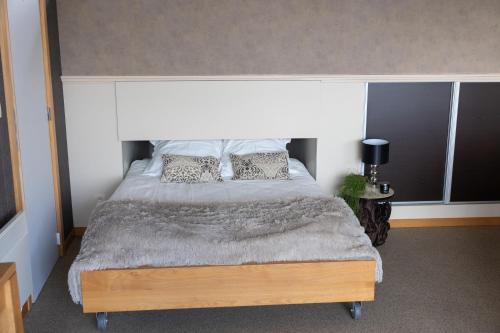 ein Schlafzimmer mit einem großen Bett mit Kissen darauf in der Unterkunft Le Petit Logis in Jalhay