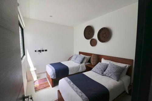 トゥルムにあるAmazing!! PH 2 Bdrm + Private Rooftop &Pool /Aldea Zamaのベッドルーム1室(ベッド2台、壁掛け時計付)