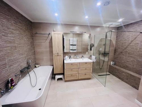 een badkamer met een bad, een wastafel en een douche bij Windsor Residence Grimbergen in Grimbergen