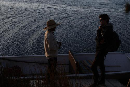 two people standing on a boat near the water at Uros Lodge Perú in Puno