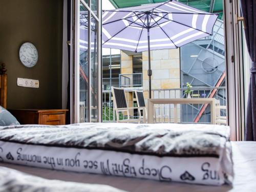 a bed with an umbrella in front of a balcony at Minjo Hotel in Bad Kreuznach
