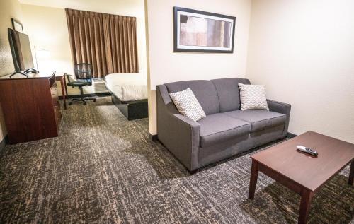 una sala de estar con sofá en una habitación de hotel en Cobblestone Hotel & Suites - Lamar, en Lamar