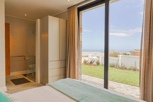 a bedroom with a large glass door leading to a bathroom at The View, Apartment, with magnificent sea view in Hermanus