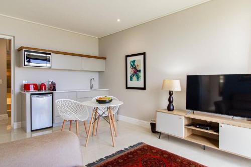 a living room with a tv and a table with chairs at The View, Apartment, with magnificent sea view in Hermanus