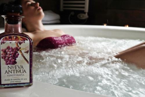 a woman in a bath tub with a bottle of alcohol at El Molí de Pontons suites con jacuzzi spa in Pontons