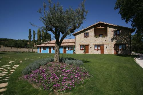 a house with a tree and flowers in front of it at Le Calvie, country house in Camerino