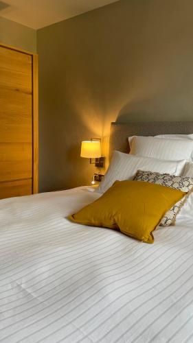 a large white bed with a yellow pillow on it at LES GITES DE LA KARLSMUHLE in Haguenau