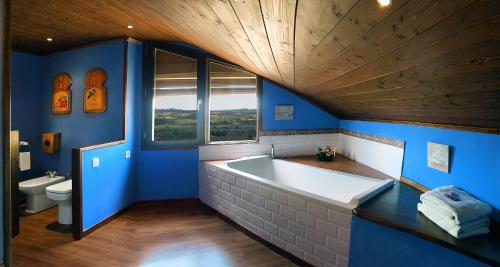 uma casa de banho azul com uma grande banheira e um WC em Hotel rural reina Berta em Murillo de Gállego