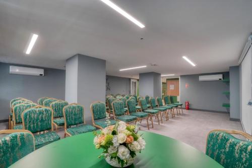 a conference room with green chairs and a table with flowers at İbos Hotels Izmir in Izmir