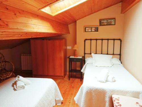 1 dormitorio con 2 camas y techo de madera en Casa Pelayo 2, en Poo de Cabrales