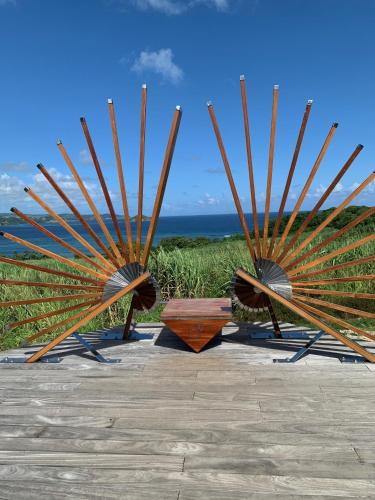 a group of three wooden benches with the ocean in the background at Sous les tropiques in La Trinité