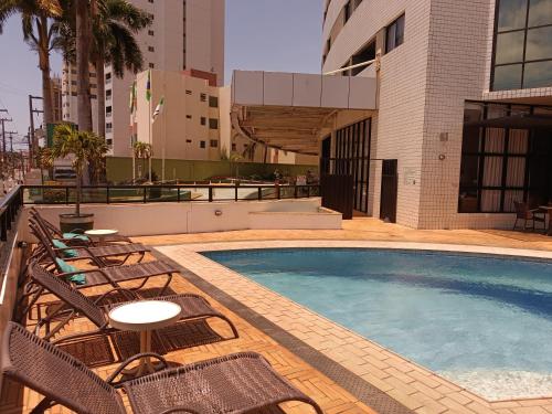 a swimming pool with lounge chairs and a building at Suíte acolhedora em Hotel in Natal