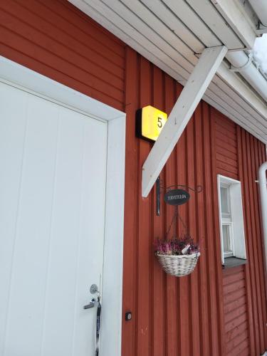 a door to a red building with a basket of flowers at Rivitaloasunto Kittilässä in Kittilä