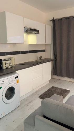 eine Küche mit einer Waschmaschine und einem Waschbecken in der Unterkunft Cosy Studio Flat in Kensington in London