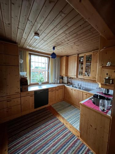 a kitchen with wooden cabinets and a large window at hAUSzeit - Bungalow in Leoben
