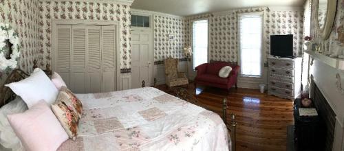 um quarto com uma cama e uma cadeira vermelha em Historic Seaton Springs Farm B&B - M Seaton Queen Room with Private Bath down the hall em Sevierville