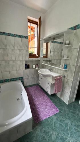 a bathroom with a tub and a sink and a mirror at hAUSzeit - Bungalow in Leoben