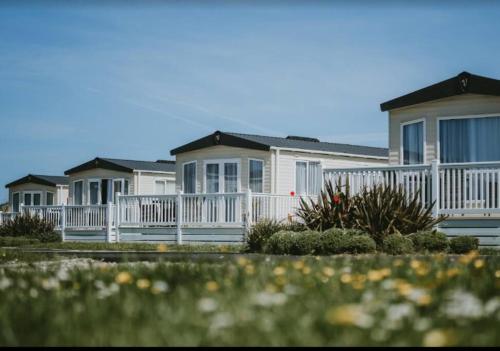 a row of houses with a white fence at Cornwall Holiday Cabin with Hot tub & Sea view in Cubert