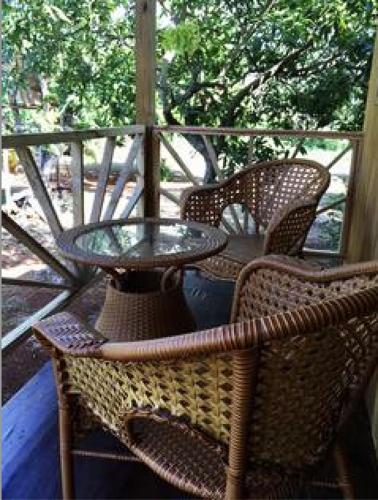 a glass table and wicker chairs on a porch at BnB SoMom Mobay Lodging in Montego Bay