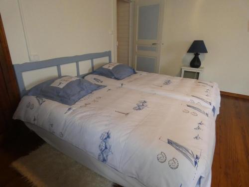 a bed with a blue and white comforter on it at Gite bonnebat in Lacrabe
