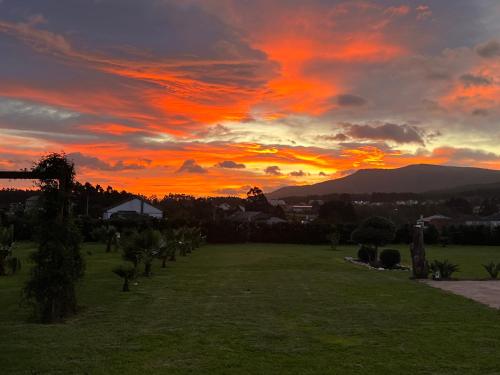 a sunset over a grassy field with the sun setting at Casal de pelaio in Barreiros