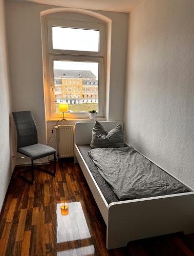 馬格德堡的住宿－Mitten in Magdeburg，卧室配有床、椅子和窗户。