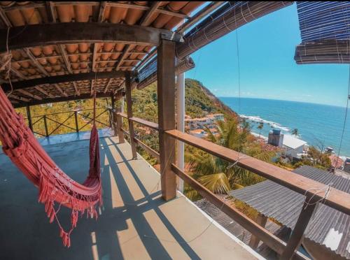 a hammock on a balcony overlooking the ocean at Morro Hostel e Pousada in Morro de São Paulo