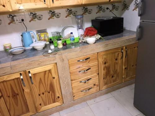 a kitchen counter with wooden cabinets and a refrigerator at Sohna's Paradise Residence 