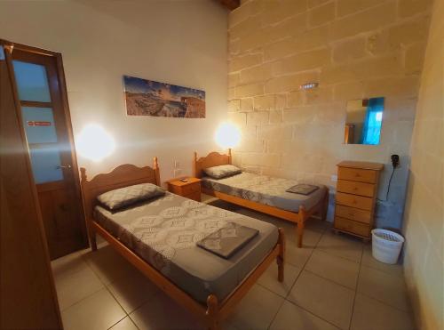 a small room with two beds and a dresser at Margerita Farmhouse in Qrendi