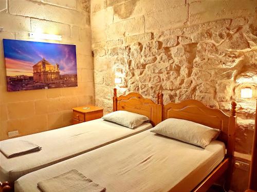 two beds in a room with a stone wall at Margerita Farmhouse in Qrendi
