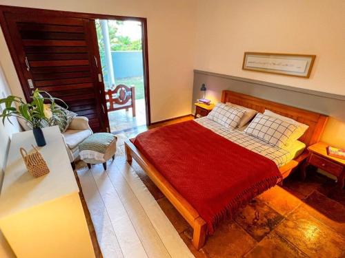 een slaapkamer met een bed met een rode deken bij Casa Araçá - 3 qt. no centro in Pipa