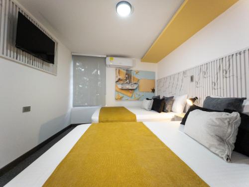 a room with two beds and a flat screen tv at Hotel velero in Roldanillo