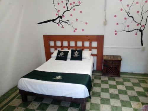a bedroom with a bed with a tree on the wall at Hotel Don Pedro in Puebla