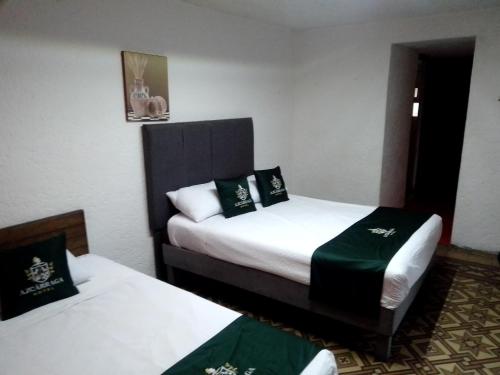 a hotel room with two beds with green sheets at Hotel Don Pedro in Puebla