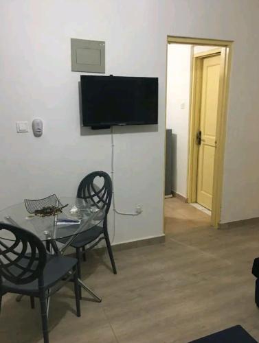 a living room with a table and chairs and a television at Lovely 1-bedroom rental unit for short stays. in Tema