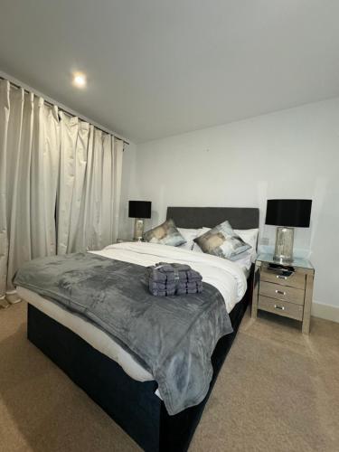 Luxe Lodge Woolwich Arsenal في Woolwich: غرفة نوم بسرير كبير وموقف ليلي مع مصباح