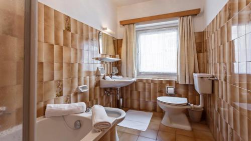 a bathroom with a toilet and a sink and a tub at Apartments Villa Alpina in Santa Cristina in Val Gardena