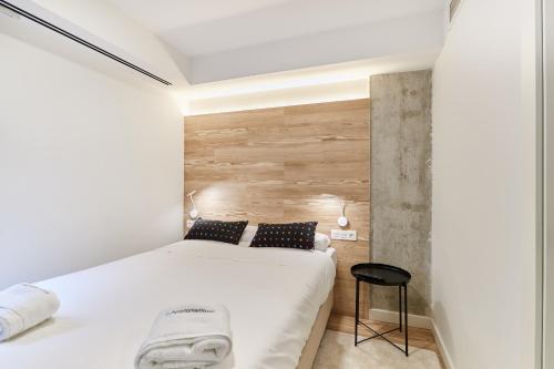 a bedroom with a white bed and a wooden wall at TuApartamento Boutique & Art - Corralillos del Gas in Pamplona