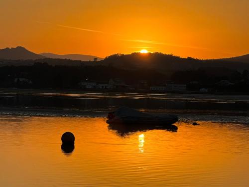a boat in the water with the sunset in the background at Casal de pelaio in Barreiros