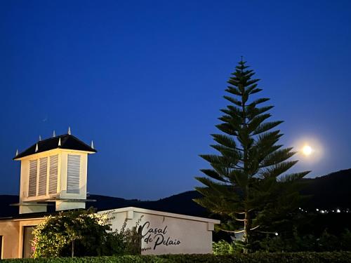 a pine tree in front of a building with the moon at Casal de pelaio in Barreiros