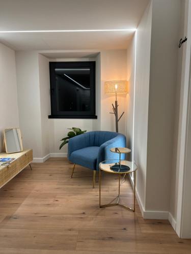a living room with a blue chair and a tv at Casal de pelaio in Barreiros