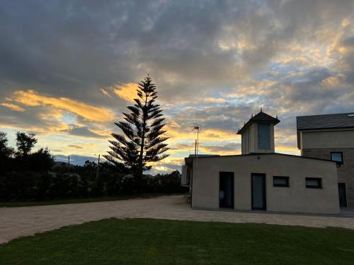 a building with a tree in front of a sunset at Casal de pelaio in Barreiros