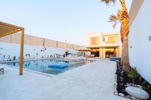 a swimming pool next to a building with a palm tree at Nammos Experience in Amman