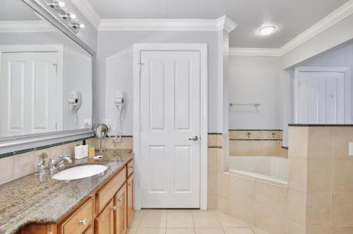 a bathroom with a sink and a tub and a white door at New In The Market 3bd Apartment With Wide View! in Kissimmee