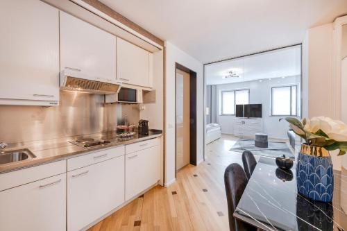 a kitchen with white cabinets and a table with chairs at Milan Royal Suites - Centro in Milan