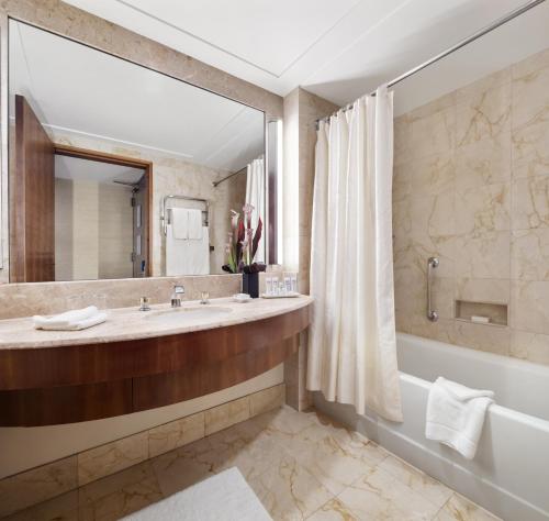 baño con espejo grande, bañera y lavamanos en The Prince Kitano New York en Nueva York