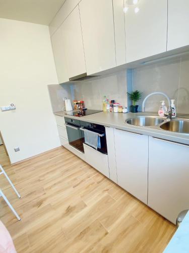 a kitchen with white cabinets and a wooden floor at Apart WIKTORIA in Warsaw